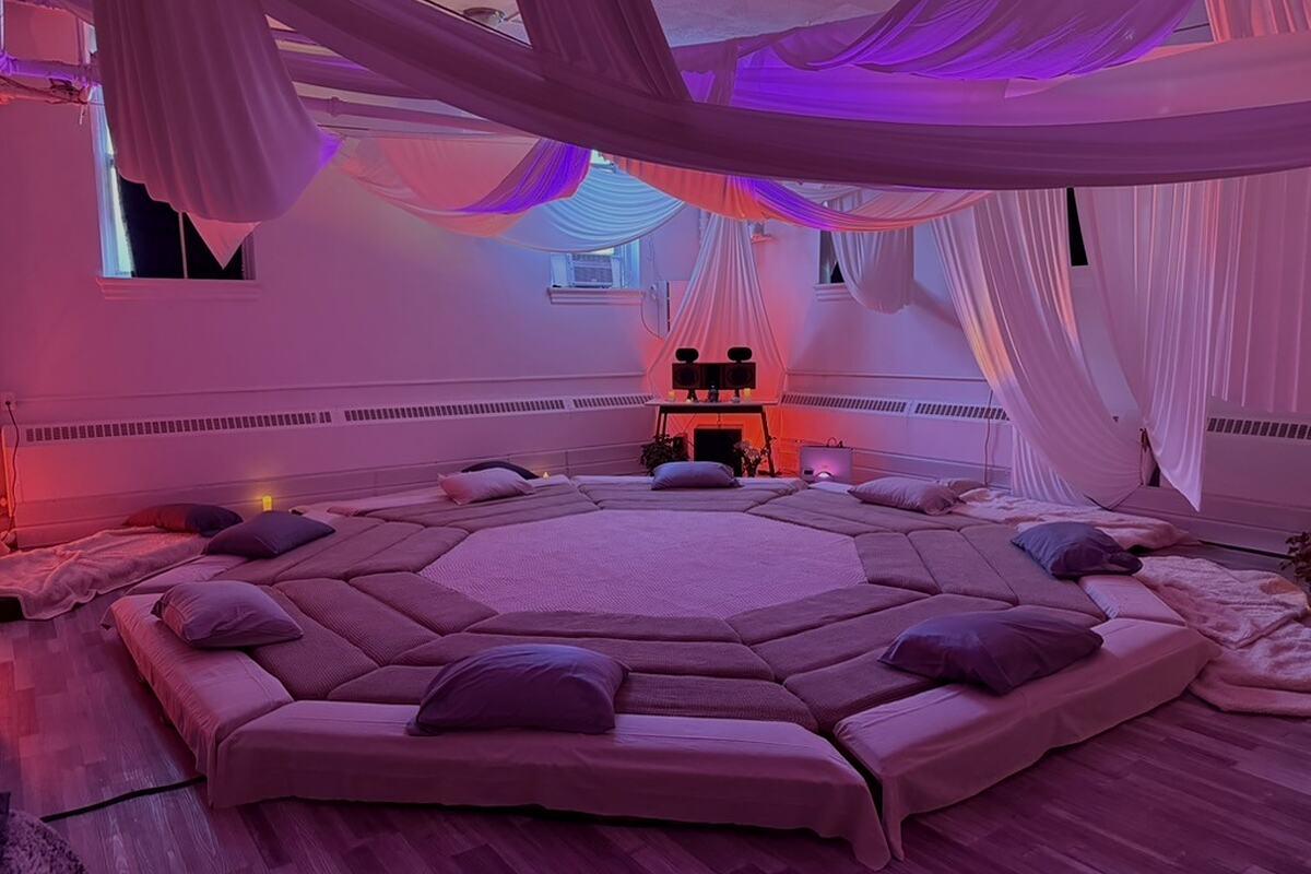 The SoundTemple room empty and lit violet: AVA laid out with its pads and cushions under draped ceiling fabric.