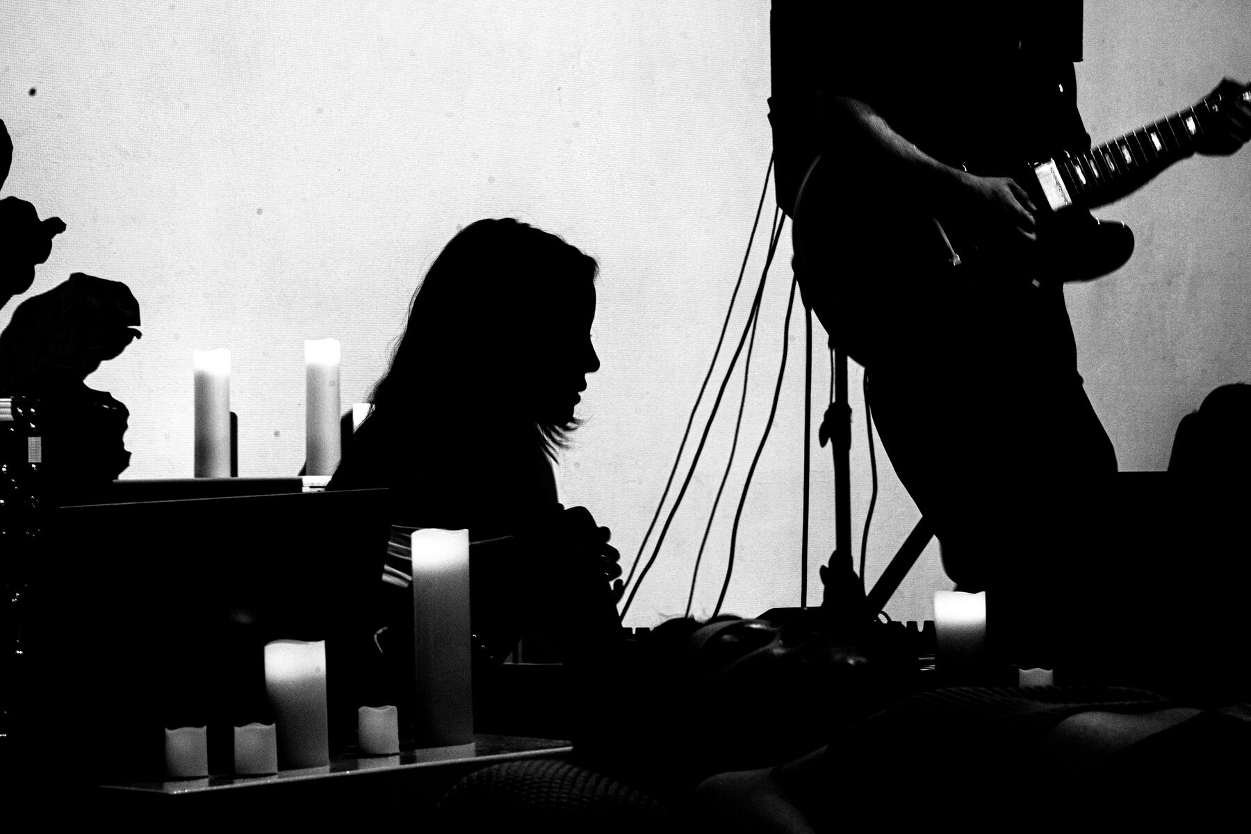 Silhouettes at the console and a guitar, candles along the ledge.